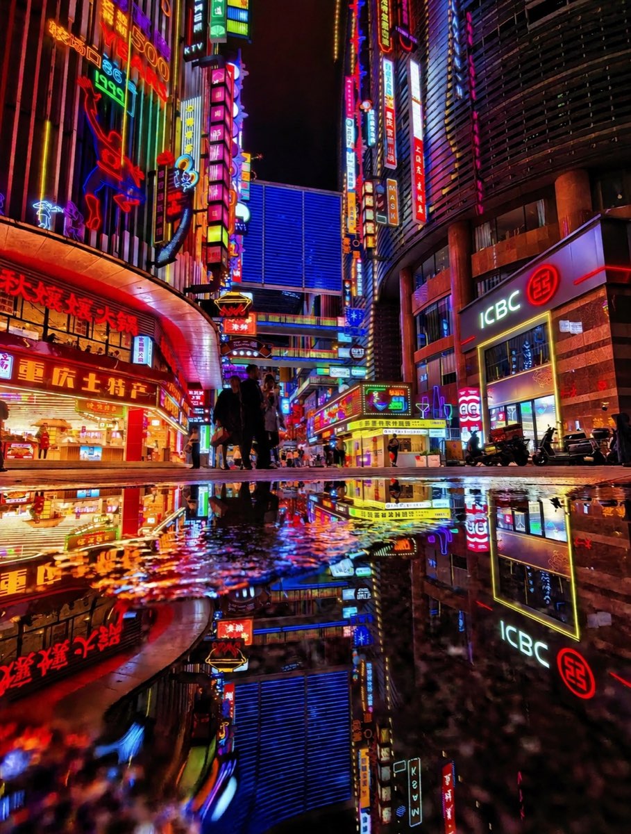 Neon signs and wet streets in central Jiefangbei after dark